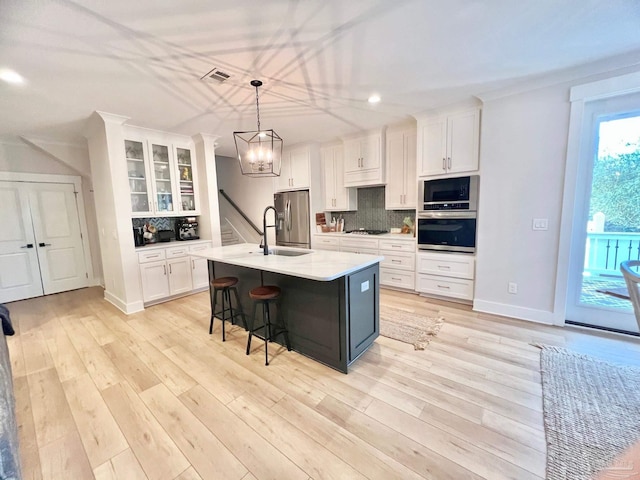 4979 Leeward Dr, Pensacola, FL 32507 - kitchen with white cabinetry, light countertops, a kitchen bar, backsplash, and appliances with stainless steel finishes