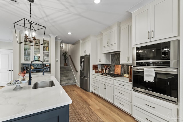 4979 Leeward Dr, Pensacola, FL 32507 - kitchen featuring a sink, decorative backsplash, appliances with stainless steel finishes, white cabinetry, and a notable chandelier