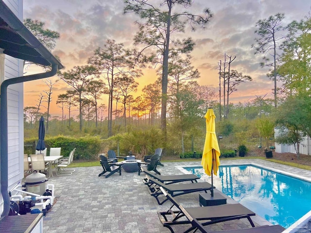 4979 Leeward Dr, Pensacola, FL 32507 - pool at dusk with outdoor dining space, a patio area, a fenced in pool, and an outdoor fire pit