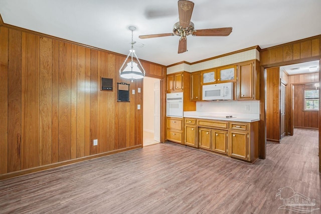 kitchen featuring white appliances, wood finished floors, brown cabinetry, and light countertops