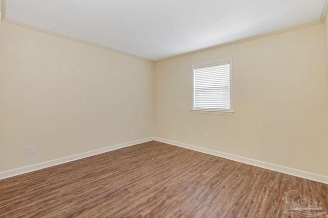 spare room with crown molding, wood finished floors, and baseboards