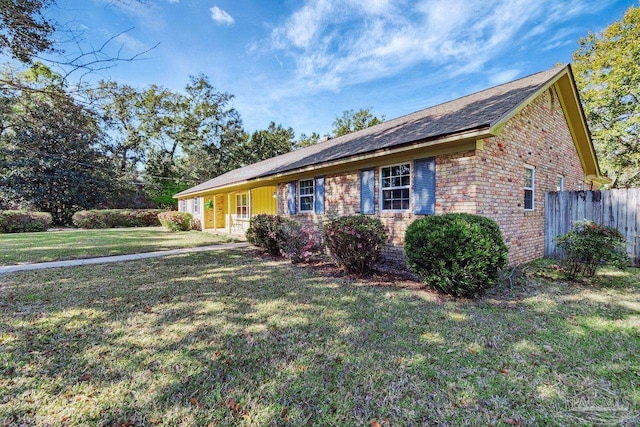 ranch-style home with brick siding, a front lawn, and fence