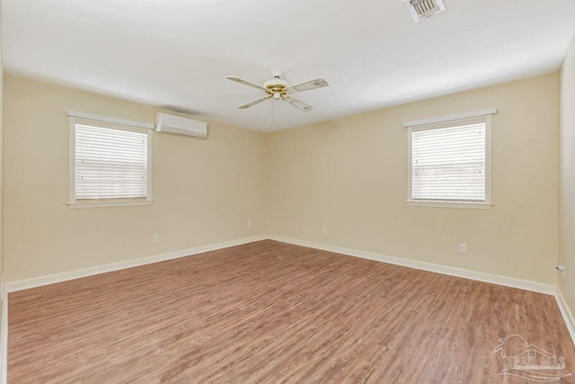 unfurnished room featuring visible vents, baseboards, ceiling fan, an AC wall unit, and light wood-style flooring