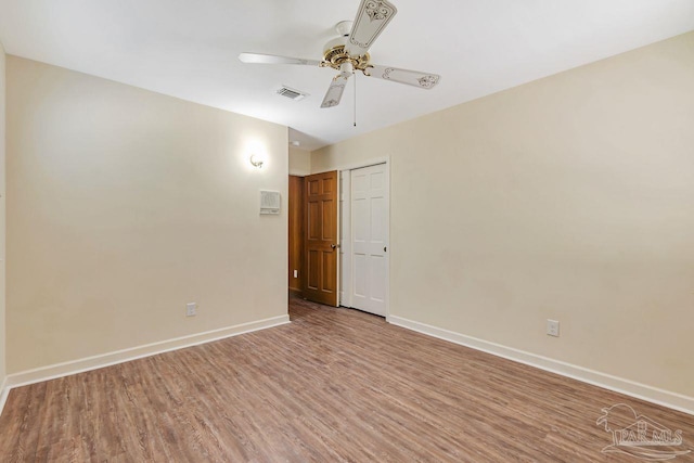 empty room featuring visible vents, wood finished floors, baseboards, and ceiling fan