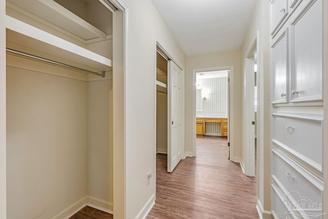 corridor featuring baseboards and wood finished floors