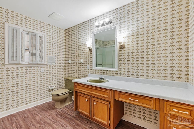 bathroom with toilet, wallpapered walls, and wood finished floors