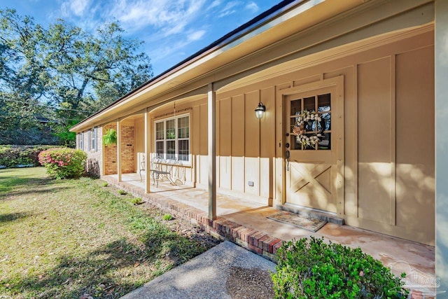 entrance to property featuring a porch, a lawn, and board and batten siding