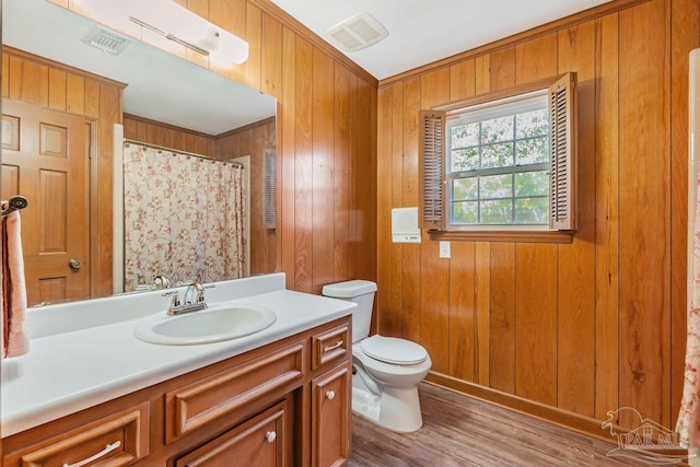 full bath with vanity, wooden walls, toilet, and visible vents