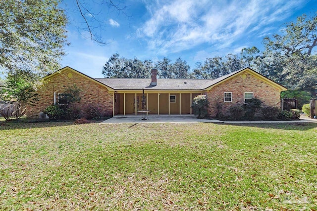 back of property featuring brick siding, a patio area, and a lawn