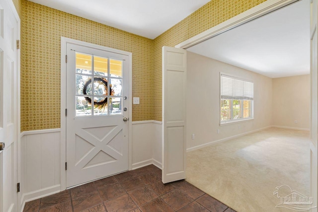 entryway with a wainscoted wall, dark carpet, and wallpapered walls