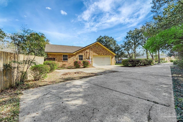 view of front of home featuring an attached garage, fence, brick siding, and driveway