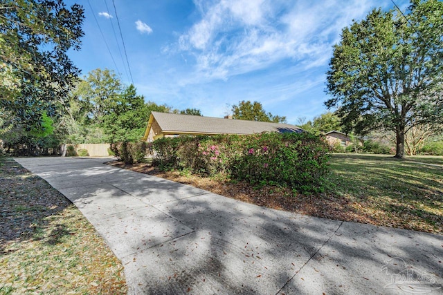 view of property exterior featuring a lawn, driveway, and fence