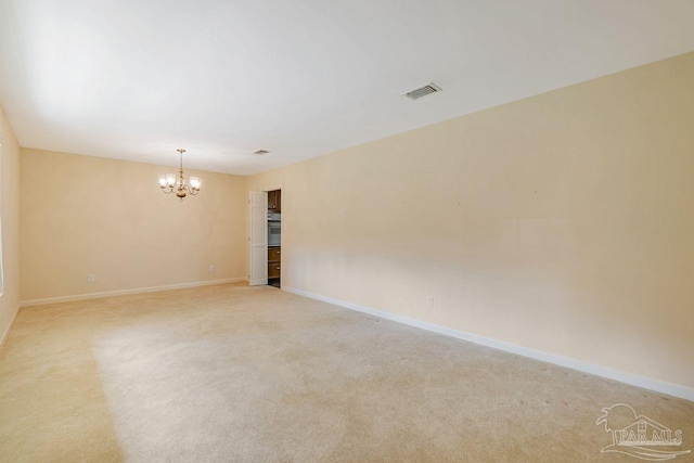 unfurnished room with visible vents, light colored carpet, baseboards, and an inviting chandelier