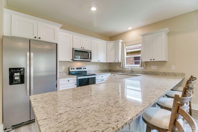 kitchen with stainless steel appliances, white cabinetry, light wood-type flooring, and recessed lighting