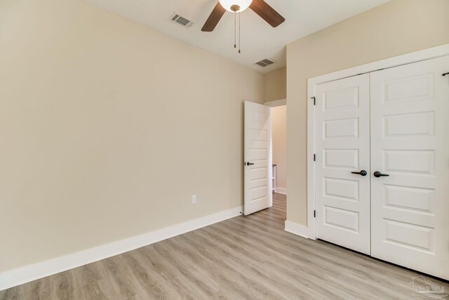 unfurnished bedroom featuring light wood-style floors, a closet, baseboards, and a ceiling fan
