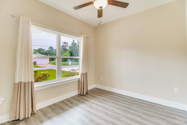 spare room featuring light wood-type flooring, a ceiling fan, and baseboards