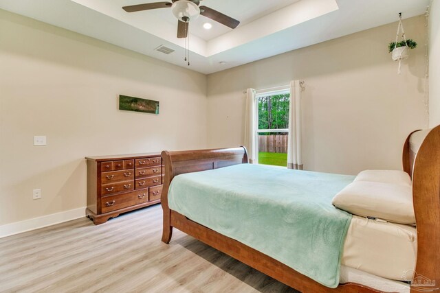 bedroom featuring wood finished floors, a tray ceiling, baseboards, ceiling fan, and recessed lighting