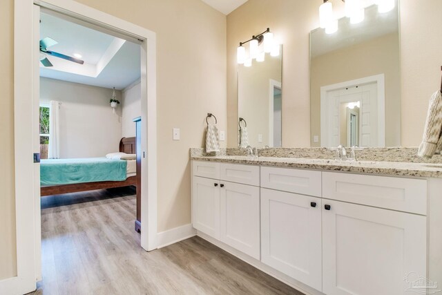bathroom with wood finished floors, connected bathroom, baseboards, and double vanity