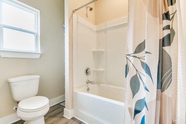 full bathroom featuring baseboards, toilet, wood finished floors, and shower / bath combination with curtain