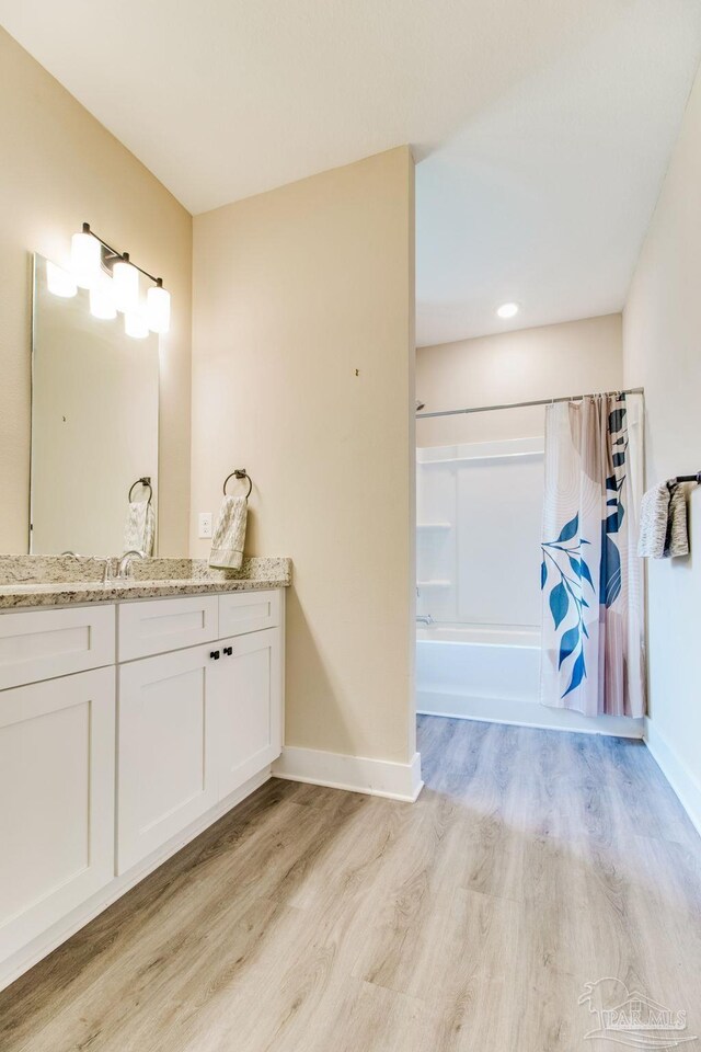 full bathroom featuring wood finished floors, shower / tub combo with curtain, vanity, and baseboards