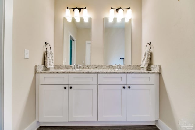 full bath featuring double vanity and baseboards