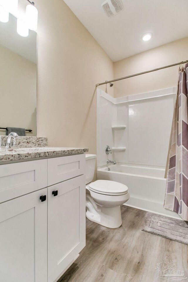 full bathroom featuring wood finished floors, toilet, shower / bathtub combination with curtain, and vanity
