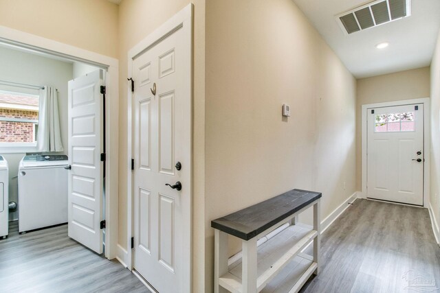 entryway featuring washing machine and dryer, light wood-style floors, and baseboards