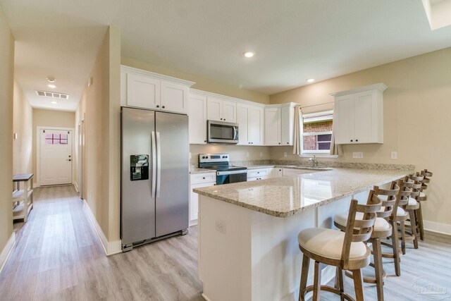 kitchen featuring stainless steel appliances, light wood-style floors, white cabinetry, a peninsula, and recessed lighting
