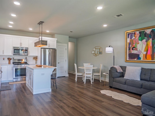 817 N D St, Pensacola, FL 32501 - kitchen with open floor plan, white cabinets, dark wood-type flooring, a breakfast bar area, and stainless steel appliances