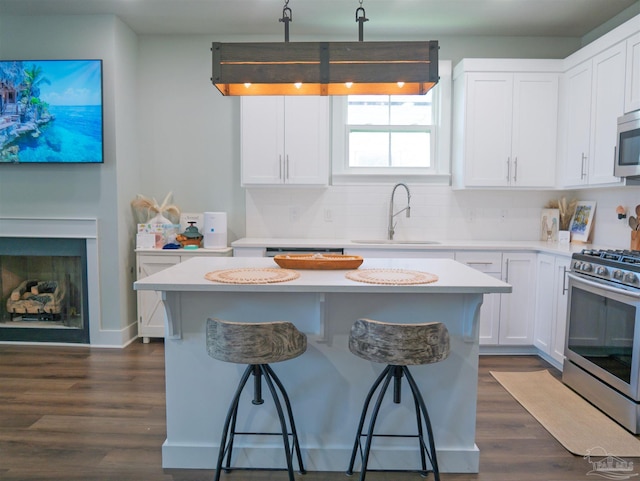 817 N D St, Pensacola, FL 32501 - kitchen featuring white cabinets, a sink, appliances with stainless steel finishes, a kitchen breakfast bar, and dark wood finished floors