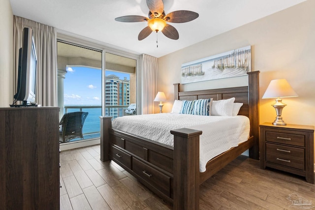 bedroom with a water view, ceiling fan, wood-type flooring, and access to exterior