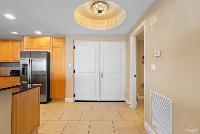 kitchen with backsplash, a raised ceiling, light tile patterned floors, and stainless steel fridge