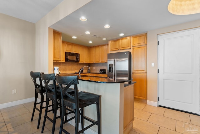 kitchen featuring stainless steel refrigerator with ice dispenser, kitchen peninsula, backsplash, light tile patterned flooring, and a kitchen bar