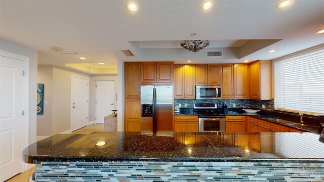 kitchen with stainless steel appliances, backsplash, sink, and a tray ceiling