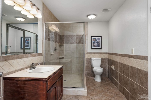 bathroom featuring walk in shower, vanity, tile walls, and toilet