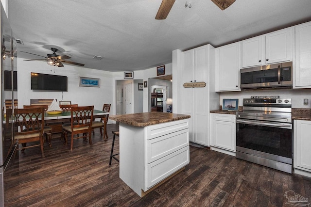 kitchen featuring stainless steel appliances, white cabinetry, a textured ceiling, and dark wood-type flooring