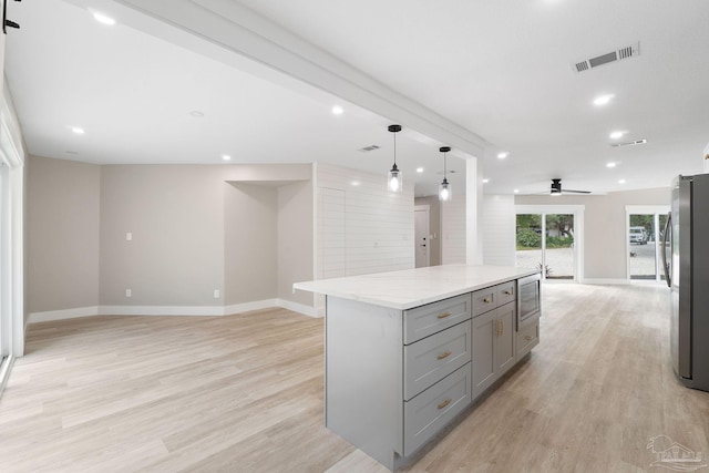 kitchen with stainless steel appliances, ceiling fan, a center island, light hardwood / wood-style floors, and hanging light fixtures