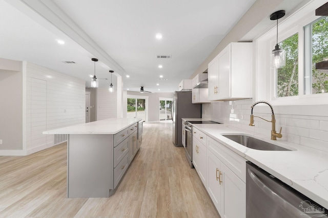 kitchen with white cabinetry, light stone counters, pendant lighting, decorative backsplash, and appliances with stainless steel finishes