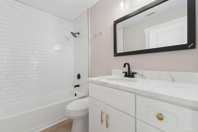 full bathroom with toilet, vanity, wood-type flooring, and tiled shower / bath