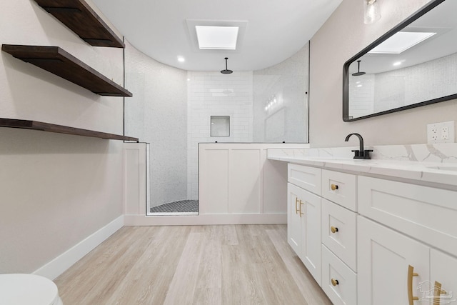 bathroom with a tile shower, vanity, and hardwood / wood-style flooring