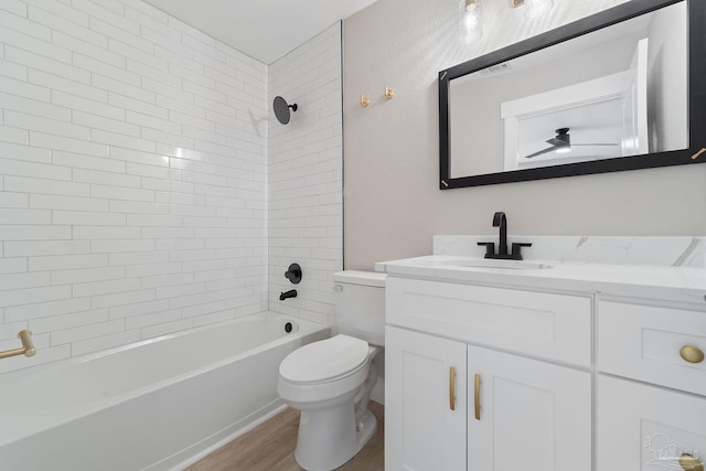 full bathroom featuring hardwood / wood-style floors, tiled shower / bath combo, toilet, and vanity