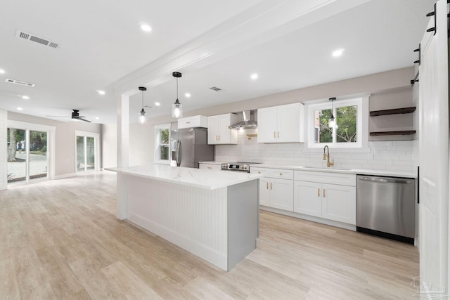 kitchen with white cabinets, ceiling fan, a kitchen island, and stainless steel appliances