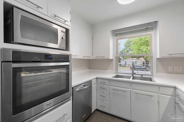 770 Connell Dr, Pensacola, FL 32503 - kitchen with stainless steel appliances, light countertops, white cabinets, a sink, and ornamental molding