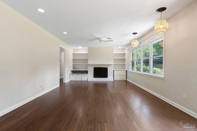 770 Connell Dr, Pensacola, FL 32503 - unfurnished living room featuring baseboards, a ceiling fan, a brick fireplace, dark wood-style flooring, and built in features
