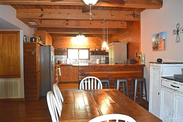 dining area with wood walls, beam ceiling, and dark wood-type flooring