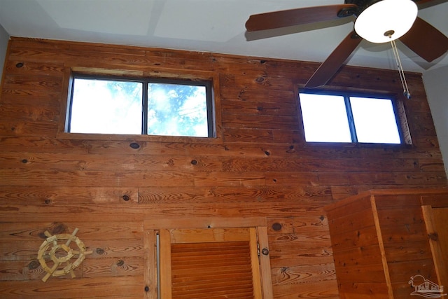 interior details with ceiling fan and wood walls