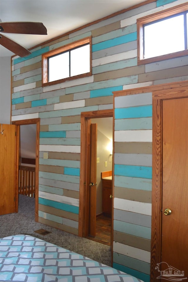 unfurnished bedroom featuring dark colored carpet, connected bathroom, multiple windows, and ceiling fan