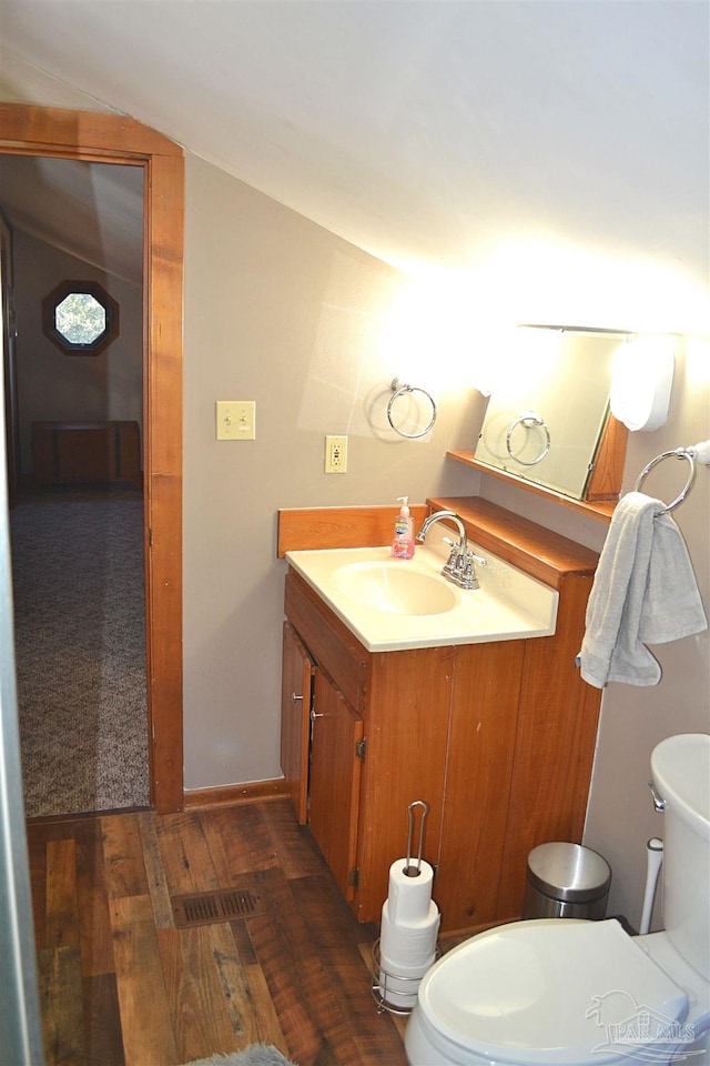 bathroom with vanity, hardwood / wood-style flooring, toilet, and lofted ceiling