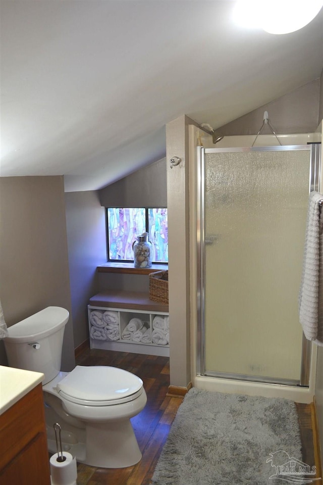 bathroom featuring vaulted ceiling, toilet, a shower with door, vanity, and hardwood / wood-style flooring