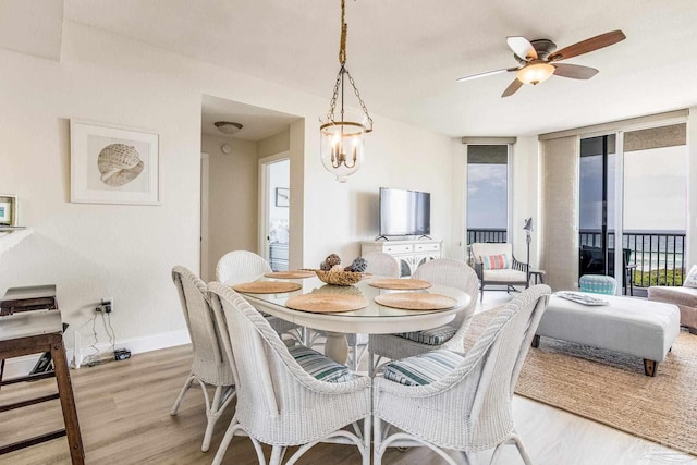 dining space featuring ceiling fan with notable chandelier and light hardwood / wood-style flooring